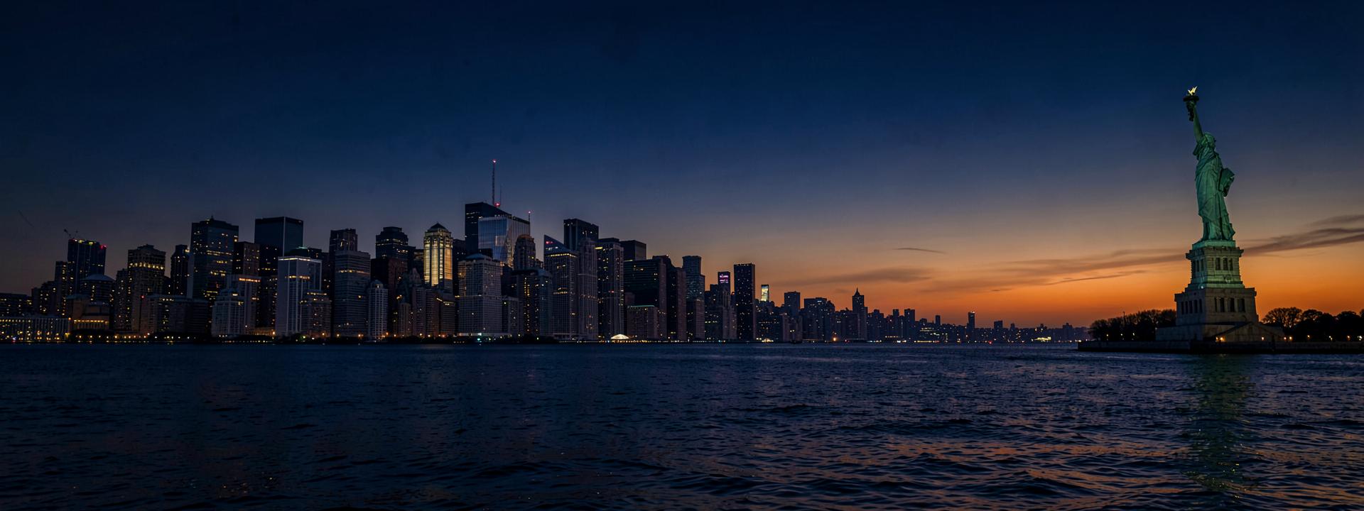 New York City skyline at dusk with the Statue of Liberty